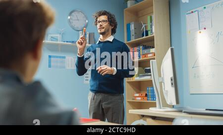 Insegnante entusiasta spiega la lezione a un'aula piena di bambini variegati e conduce la lezione con fare domande. Nel gruppo della scuola elementare di Foto Stock