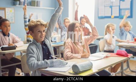 L'insegnante spiega la lezione a un'aula di bambini brillanti, fa domande. In Elementary School Group di Bright multietnic Kids Learning Foto Stock