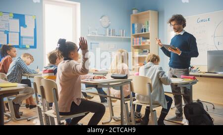 L'insegnante premuroso spiega la lezione a un'aula piena di bambini variegati e luminosi. In scuola elementare con Gruppo di Smart Multetnic Learning Science Foto Stock