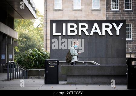 Uno studente che indossa una maschera protettiva al di fuori della biblioteca principale dell'Università di Edimburgo a George Square, Edimburgo, dopo che il primo ministro Nicola Sturgeon ha annunciato una serie di nuove misure per combattere l'aumento dei casi di coronavirus in Scozia. Foto Stock