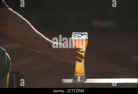 Silhouette di mano che raggiunge per un bicchiere di birra al siero di latte. Foto Stock