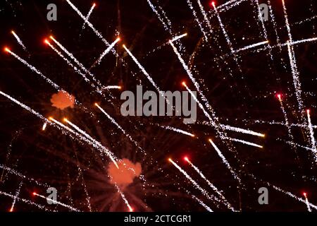 Sfondo festivo raggi rossi di fuochi d'artificio su uno sfondo scuro. Foto Stock