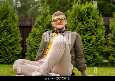 Felice giovane bell'uomo con le cuffie che riposano sull'erba Foto Stock