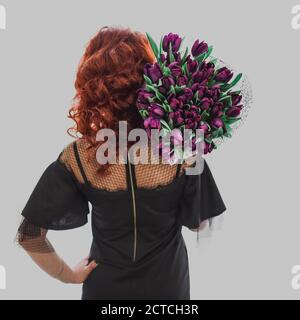 La giovane ragazza le tiene un bouquet di tulipani viola spalle Foto Stock