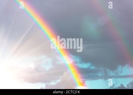 Vero arcobaleno con luce solare brillante e raggi solari in il cielo tra le nuvole dopo la pioggia Foto Stock