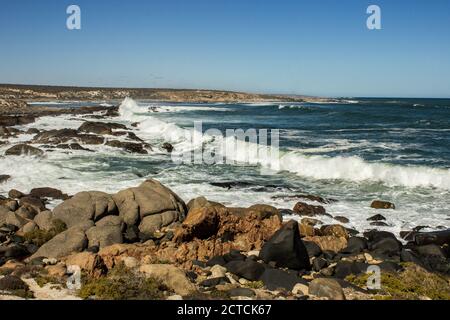 Onde che si infrangono lungo la costa occidentale rocciosa del Sud Africa, fotografate nella sezione costiera del Parco Nazionale di Namaqua in una giornata di sole Foto Stock