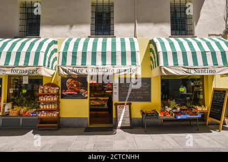 Esterno di un negozio di alimentari che vende prodotti tipici con frutta e verdura esposti sul marciapiede nella città alpina, Courmayeur, Aosta, Italia Foto Stock