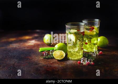 Due bicchieri con lime limonata con timo, mirtillo e ghiaccio su fondo chiaro. Rinfrescanti cocktail estivi, alcolici o non, fatti in casa o D Foto Stock