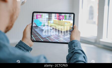 Appartamento di decorazione: Uomo Holding Tablet digitale con AR Interior Design Software sceglie mobili 3D per la casa dal negozio online con i prezzi indicati Foto Stock