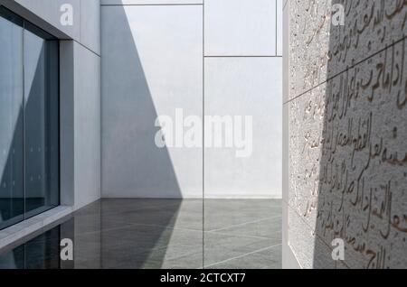 Un'immagine esterna della facciata del Louvre Abu Dhabi che include un'immagine parziale di un'installazione d'arte inscritta nella facciata accanto alle pareti e alle finestre bianche esterne. Aperto a novembre 2017. Foto Stock