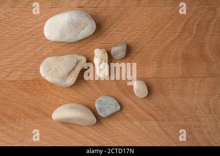 Pietre lisce di varie dimensioni sono sparse su un legno scheda Foto Stock