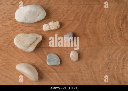 Pietre lisce di varie dimensioni sono sparse su un legno scheda Foto Stock
