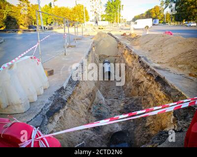 Posa di nuovi tubi in una trincea, riparazione di una rete urbana principale di riscaldamento Foto Stock