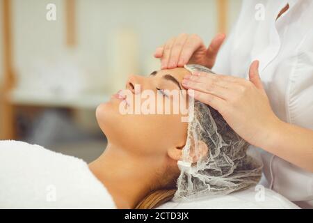 Donna che ottiene procedura di massaggio viso rilassante trattamento da cosmetologist Foto Stock