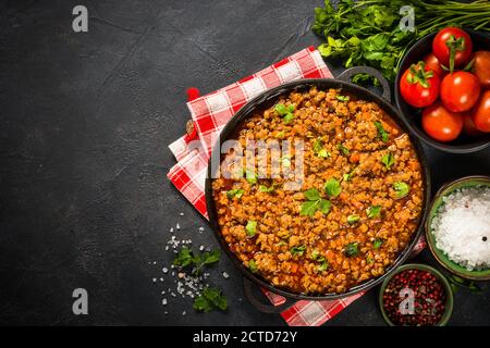 sause bolognese in piastra di ferro a tavola nera. Foto Stock