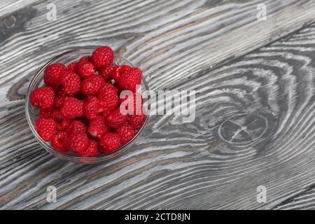 Lamponi in un contenitore di vetro. Su tavole di legno con una bella texture. Foto Stock