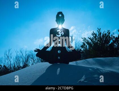 Silhouette di una persona che fa yoga con la radice chakra simbolo Foto Stock