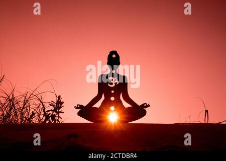 Silhouette di una persona che fa yoga con la radice chakra simbolo Foto Stock