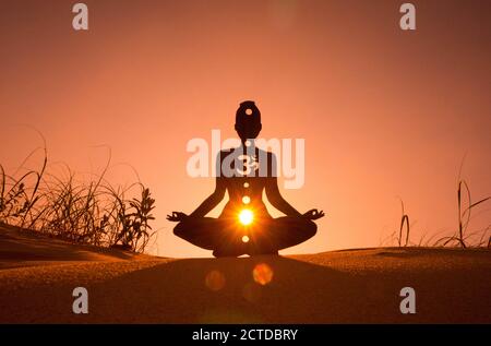 Silhouette di una persona che fa yoga con la radice chakra simbolo Foto Stock