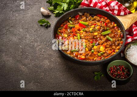 Chili con carne in padella su tavola di pietra scura. Foto Stock