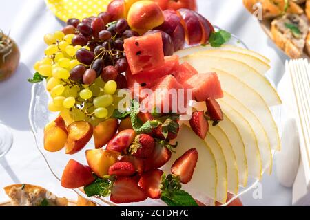 Fragole tagliate a fette, melone, pesche, uva su un piatto primo piano Foto Stock