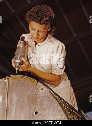 Un rivetto è la sua arma di combattimento. questo lavoratore di sesso femminile, la figlia di un tenente della marina militare, una delle tante donne che assumono NYA formazione per diventare meccanica presso la Naval Air Base, Corpus Christi, Texas. Agosto 1942 (Rosie la rivettatrice concetto) Foto Stock