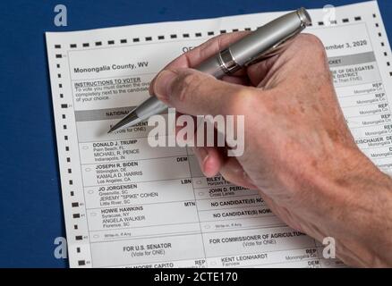 Morgantown, WV - 22 settembre 2020: Assentee della Virginia occidentale o forma di votazione Mail-in con la mano dell'uomo anziano e penna con fuoco sulla scelta del presidente Foto Stock