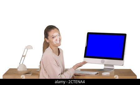 Donna affascinante che presenta qualcosa sullo schermo del computer che parla con la fotocamera schermo blu Mock-up Display su sfondo bianco. Foto Stock