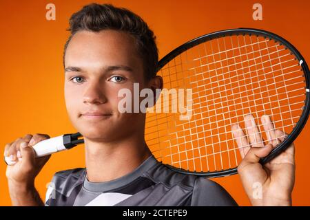 Ritratto di un giovane tennista su sfondo arancione Foto Stock