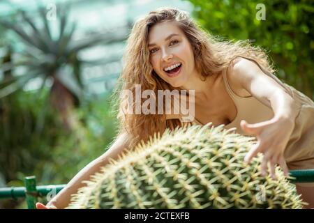 Bella giovane donna in piedi vicino al cactus e sorridente Foto Stock