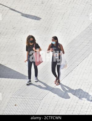 Due donne che camminano in una strada con una maschera. Foto Stock