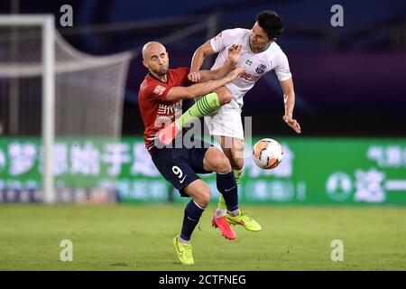 Il calciatore polacco Adrian Mierzejewski di Chongqing SWM, a sinistra, cade a terra dopo essere stato calciato durante la quarta partita di 2020 Chines Foto Stock