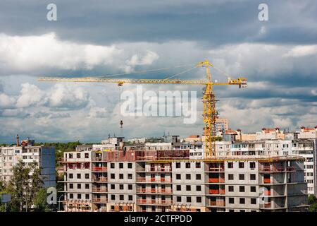 Gru di costruzione in cantiere in città su cielo nuvoloso sfondo Foto Stock