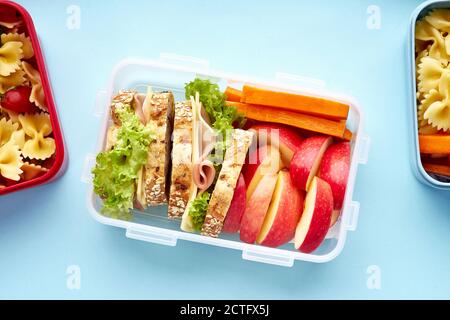 Vista dall'alto dei pranzi a scuola con vari pasti nutrienti sani su sfondo blu Foto Stock