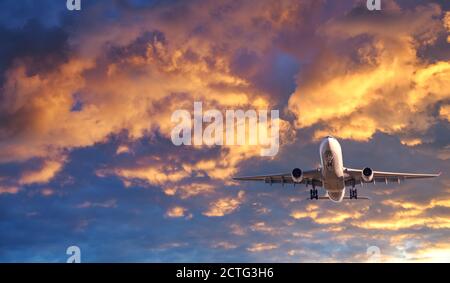 L'aereo passeggeri vola in cielo colorato al tramonto Foto Stock