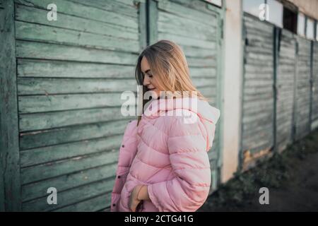 Giovane splendida ragazza bionda vestita giacca rosa moda e blu jeans Foto Stock