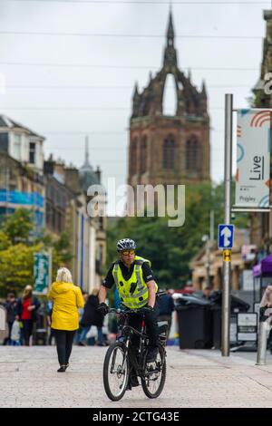 Un poliziotto è avvistato sulla High Street dal centro della città di Paisley, che, comprese altre città del Renfrewshire, ha avuto ulteriori misure di blocco aggiunto a mezzanotte la scorsa notte. A causa di un picco nei casi di Covid-19. Credito: Euan Cherry Foto Stock