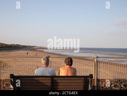 La gente ammira la vista alla fine di una giornata di sole nella località balneare di Skegness, Lincolnshire Foto Stock