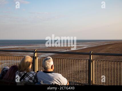 La gente ammira la vista alla fine di una giornata di sole nella località balneare di Skegness, Lincolnshire Foto Stock