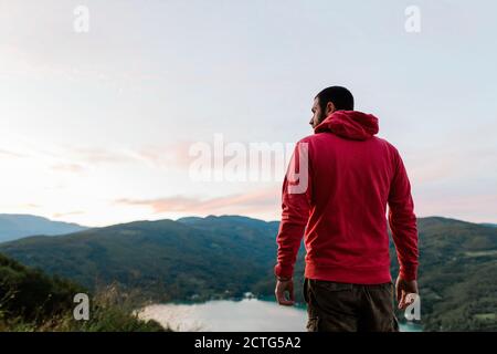 Giovane che gode della vista del lago al tramonto Foto Stock