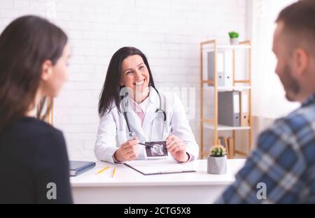 Medico amichevole che mostra ecografia a giovane coppia Foto Stock