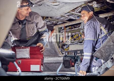 Vista laterale del ritratto degli ingegneri aeronautici che lavorano sull'area del carro con attrezzature aeronautiche all'interno di aerei commerciali Foto Stock