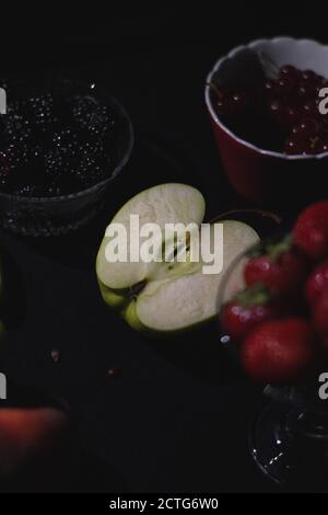 Frutti diversi insieme su sfondo nero scuro, bacche, banana, mela, lampone, mirtillo Foto Stock