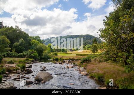 Una vista su una chiesa di San Kevin a Glendalough con un bel ruscello in primo piano Foto Stock