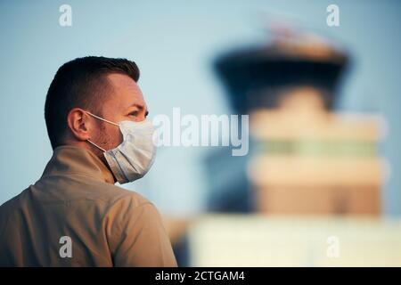 Uomo che indossa la maschera all'aeroporto. I temi viaggiano in nuova normalità, coronavirus e protezione personale. Foto Stock