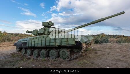 Un colpo laterale del carro armato russo T-64 nel campo. Cielo blu nuvoloso come sfondo. Foto Stock