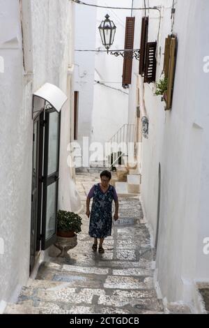 Vecchia signora locale su Vicolo Cantore Incalzi, un vicolo ripido nel centro storico di Ostuni, la Città Bianca (la Città Bianca), Puglia, Italia Foto Stock