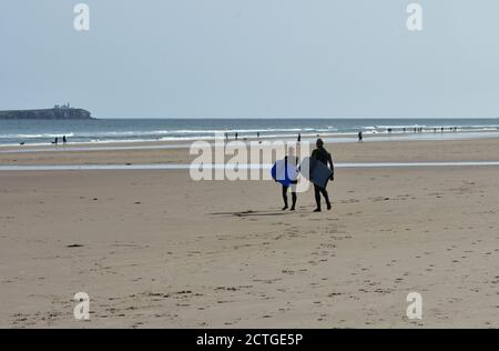 Surfers sulla spiaggia, Bamburgh, Northumberland Foto Stock