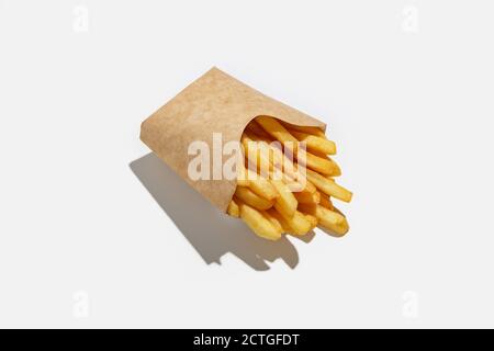 Patatine fritte e fast food da asporto nel menu durante la pandemia. Patate fritte in cartone ecologico imballo con ombra Foto Stock