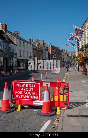 Malmesbury, Wiltshire, Inghilterra, Regno Unito. 2020, coni di traffico di distanza sociale e segnaletica nella strada principale di questa storica città mercato. Foto Stock